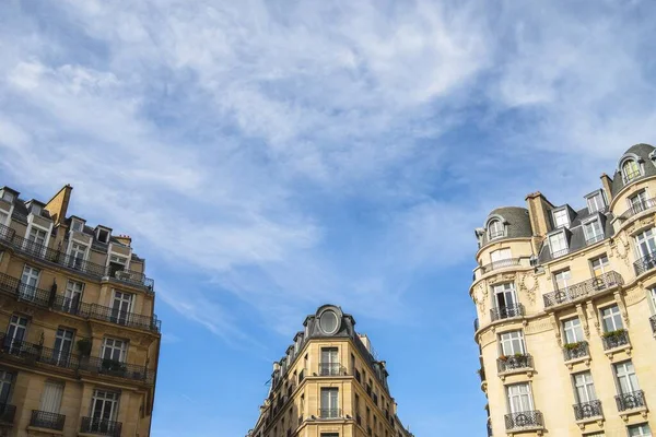 A low angle view of buildings with balconies under a blue sky and sunlight in Paris in France