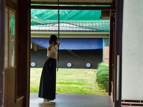 Menina segurando arco e flecha e visando um alvo em um jardim — Fotografia de Stock