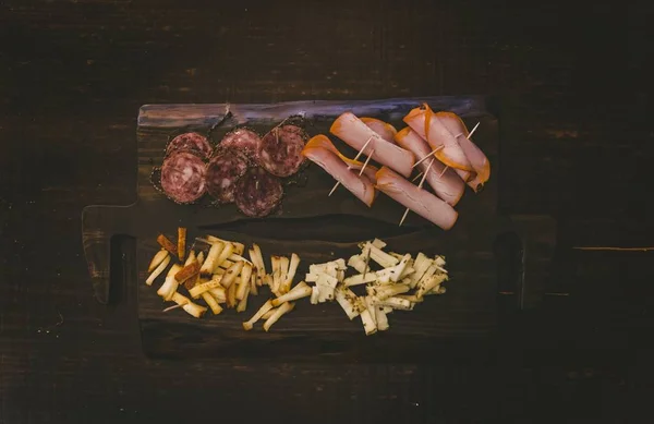 Overhead shot of a wooden tray with baloney and sliced cheese on top — 스톡 사진