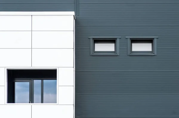 Fachada preta e branca de um edifício com as janelas refletindo o céu — Fotografia de Stock