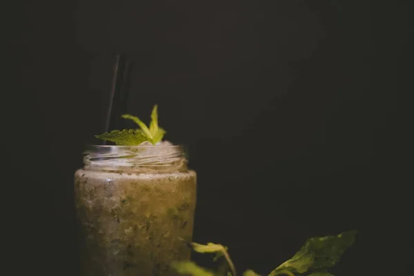 Closeup shot of a drink with a mint leaf on top and a black background — 스톡 사진