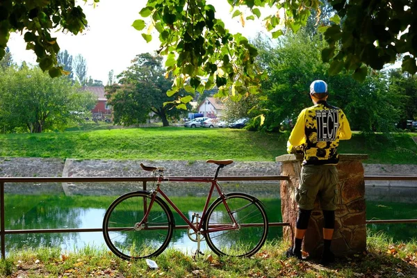 Un vélo près d'une rivière et un banc sous un arbre — Photo