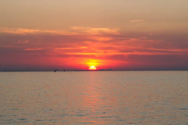 A beautiful shot of the sea with a red sun in the background