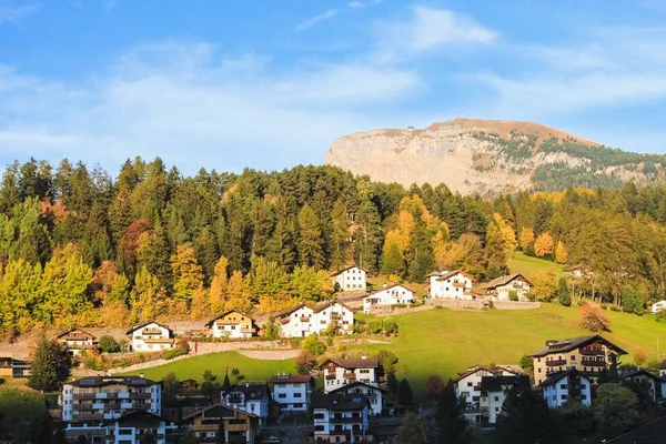 Beautiful shot of buildings on a grassy hill with a mountain in the distance at dolomite Italy — Stock Photo, Image