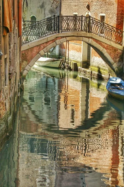 Foto vertical de un puente sobre el canal en Venecia, Italia con reflejos en el agua. — Foto de Stock