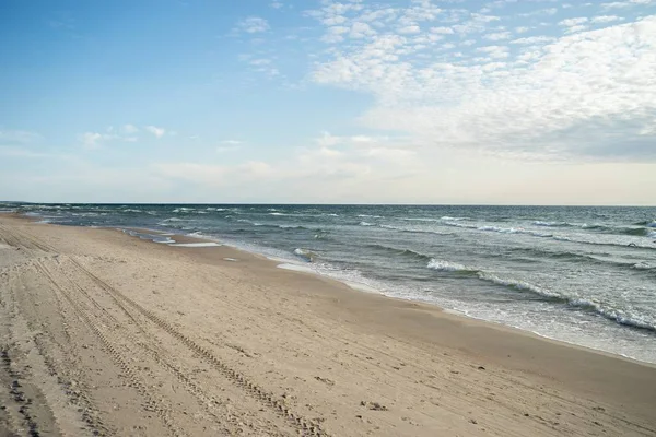 Krajobraz plaży otoczony morzem pod zachmurzonym niebem i słońcem — Zdjęcie stockowe