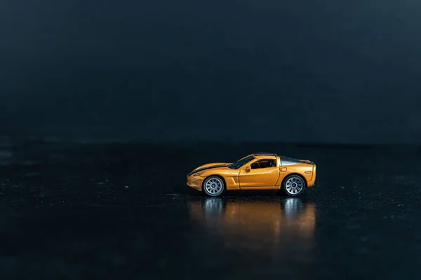 黒い表面にオレンジのおもちゃのスポーツカーの選択的フォーカスショット — ストック写真