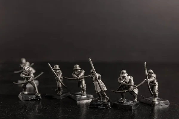 Tir sélectif en niveaux de gris des chasseurs tenant des arcs figurines — Photo