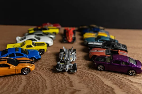 Carro esportivo de brinquedo no meio de outros carros em uma superfície de madeira — Fotografia de Stock