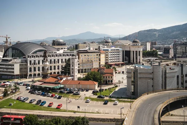 Urban area surrounded by cars and buildings with mountains covered in forests on the background — 스톡 사진