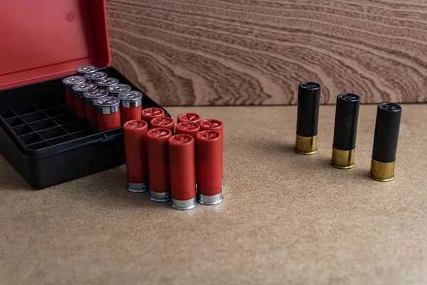 Selektywne ujęcie łuski czerwonej i czarnej strzelby w pobliżu skrzynki po amunicji na brązowej powierzchni — Zdjęcie stockowe