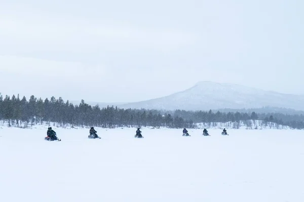 Snowy dag met mensen rijden sneeuwscooters in het noorden van Zweden — Stockfoto