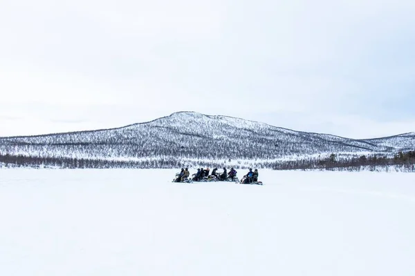 स्वीडन के उत्तर में दूर में स्नोमोबाइल पर सवार लोगों के साथ बर्फ का दिन — स्टॉक फ़ोटो, इमेज