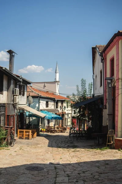 Route en pierre entourée de bâtiments et cafés sous la lumière du soleil et un ciel bleu — Photo