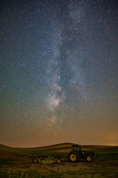 Foto vertical de un tractor en el campo con un cielo lleno de estrellas en segundo plano. — Foto de Stock