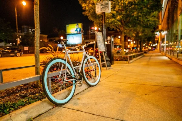 Foto selectivo de enfoque de una bicicleta inclinada contra una valla metálica en la acera. — Foto de Stock