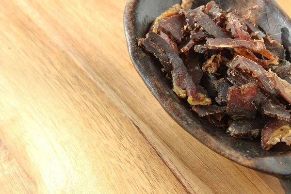 Bowl filled with traditional South African biltong on a wooden surface — 스톡 사진