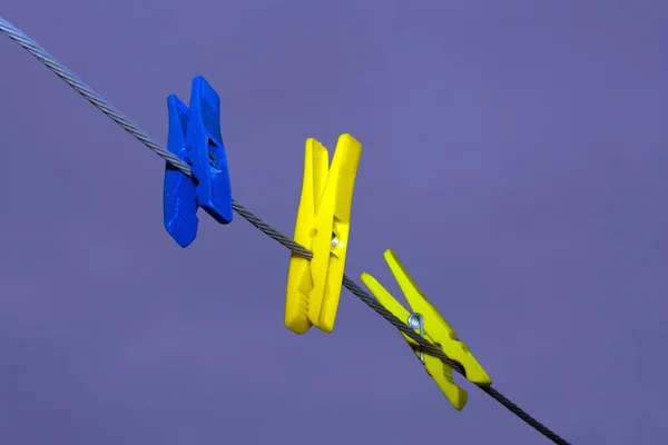 Três Pinos Coloridos Pendurados Uma Corda Com Fundo Roxo — Fotografia de Stock
