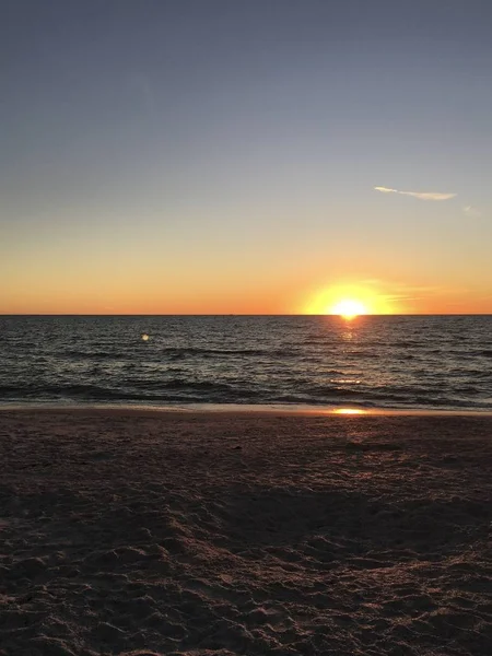 Vertical shot of the beach and the calm ocean with the breathtaking sunset in the background — 스톡 사진