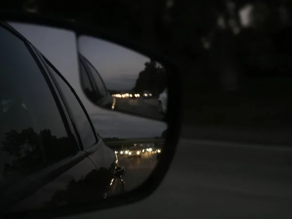Крупный план отражения черной машины в боковом зеркале на шоссе — стоковое фото