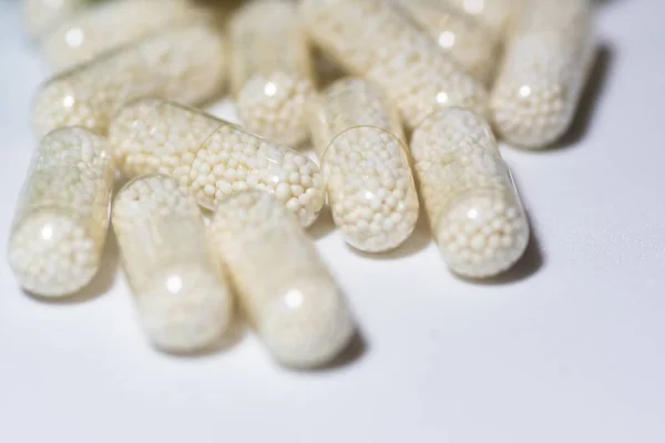 Selective focus shot of capsules on a white surface — Stock Photo, Image