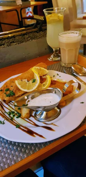 Tiro de alto ângulo de schnitzel com limões e molho branco em um restaurante — Fotografia de Stock