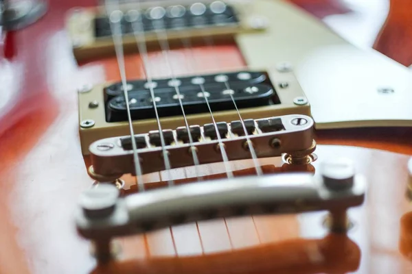 Cierre de una guitarra eléctrica roja bajo las luces con un fondo borroso. — Foto de Stock