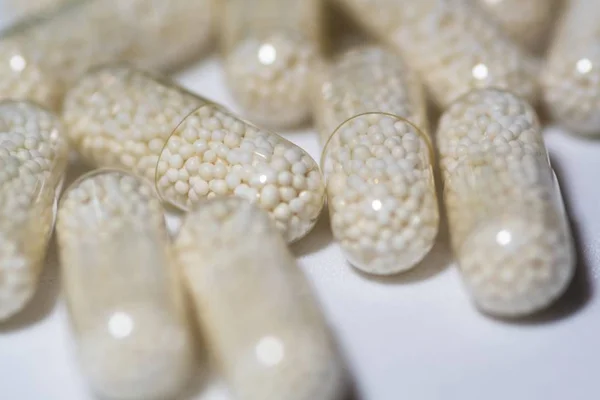 Selective focus shot of transparent capsules on a white  surface — Stock Photo, Image