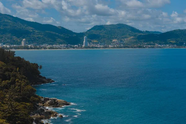 Vue en grand angle de la mer avec des bâtiments de la ville et des montagnes boisées au loin — Photo