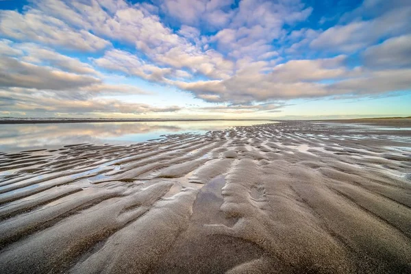 在蓝色多云的天空下 一幅幅美丽的水边湿润的沙滩照片 — 图库照片