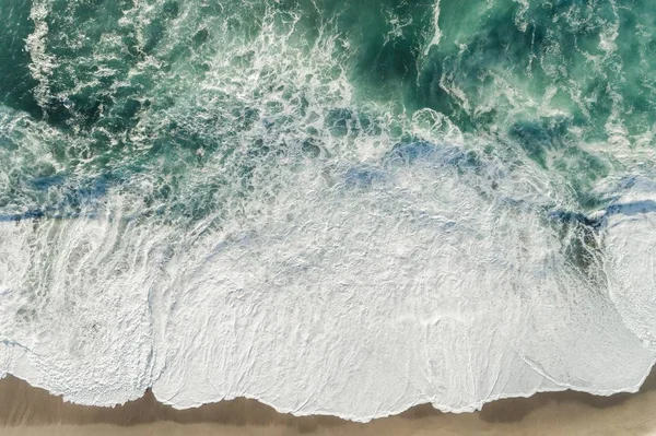 Plan à angle élevé des vagues bleues de l'océan éclaboussant le rivage — Photo
