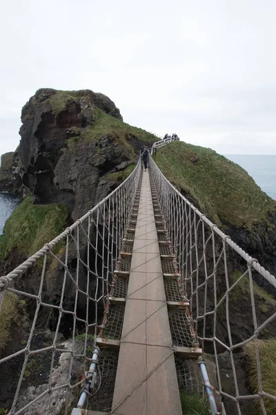 Captura vertical de alto ángulo de un puente sobre las rocas cerca del océano en Irlanda —  Fotos de Stock