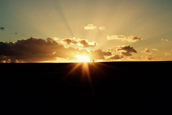 Paisagem deslumbrante do pôr do sol com o sol brilhante sobre a terra negra — Fotografia de Stock