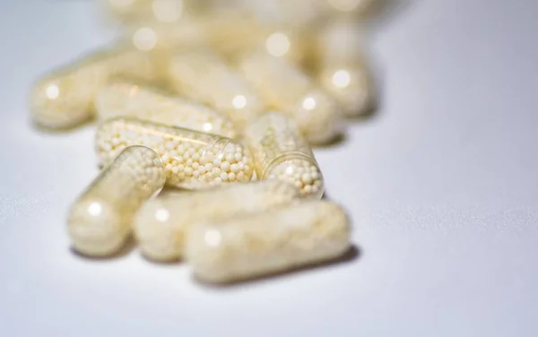 Selective focus shot of capsules pm a white surface — Stock Photo, Image