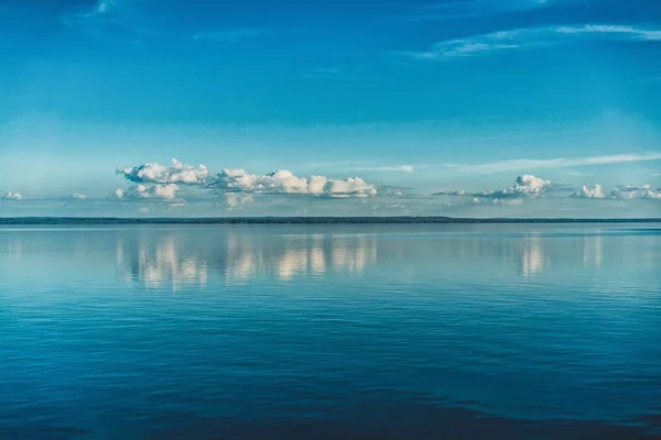 Rena vita moln av himlen reflekteras i vattnet i havet — Stockfoto