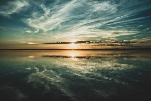 Ο ήλιος που δύει και τα σύννεφα του ουρανού αντανακλώνται στον ωκεανό από κάτω — Φωτογραφία Αρχείου