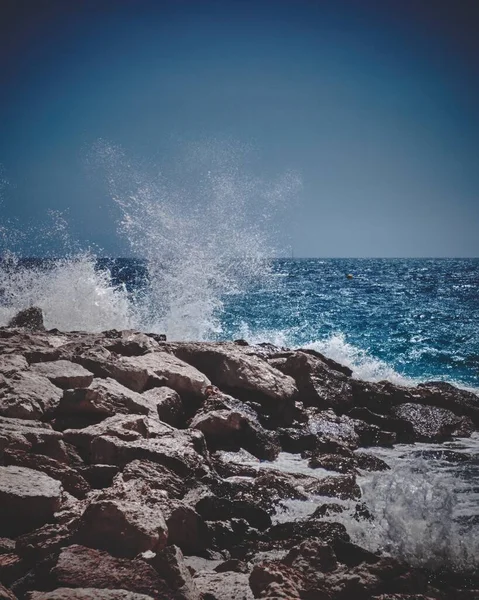 A vertical shot of the waves hitting the rocky shores captured in Cannes