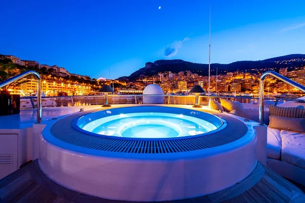 Piscina no iate e edifícios com luzes acesas na distância em Mônaco — Fotografia de Stock