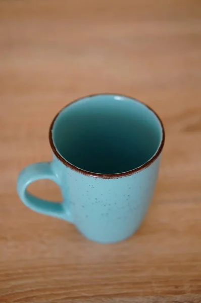 Vertikale Nahaufnahme einer hellblauen Keramiktasse auf einer Holzoberfläche — Stockfoto