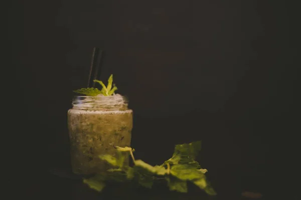 Selective focus shot of a cocktail with a mint leaf on top and a black background — 스톡 사진