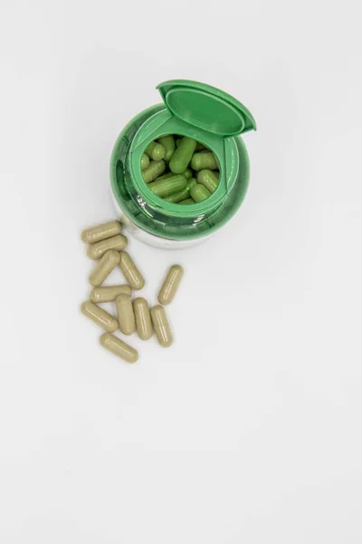 White tablets from a green pill bottle — Stok fotoğraf