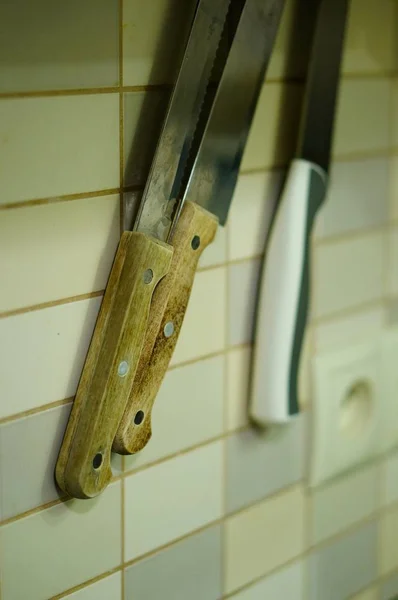 Vertikalt skott av knivar hängda på väggen med vita plattor — Stockfoto