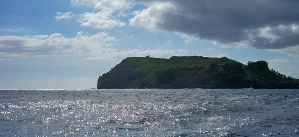 一片大海 绿油油的岩石笼罩在乌云的天空中 背景是阳光 — 图库照片