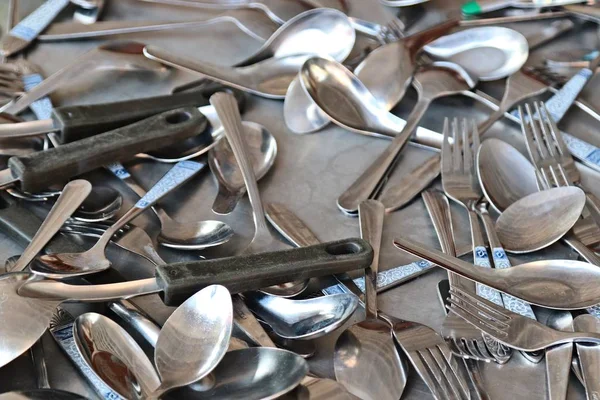 Sudut tinggi ditembak dari tumpukan sendok perak dan garpu pada permukaan logam — Stok Foto