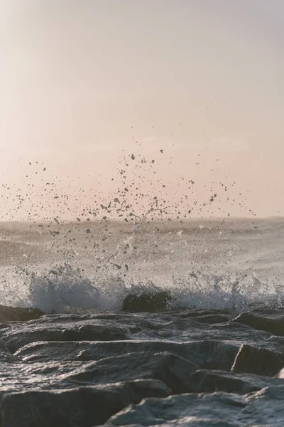 Vuelo vertical de olas de mar golpeando las rocas bajo un cielo nublado. —  Fotos de Stock