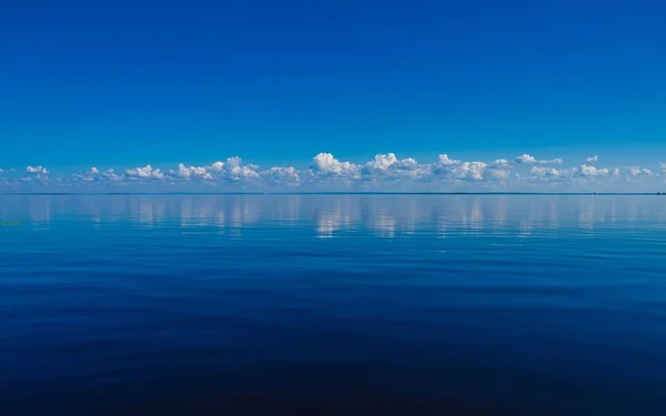 Paisagem do mar sob um céu azul com as nuvens refletindo sobre a água — Fotografia de Stock