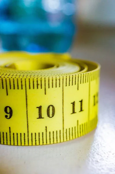 Vertical closeup shot of a yellow tape measure with a blurred background — Stock Photo, Image