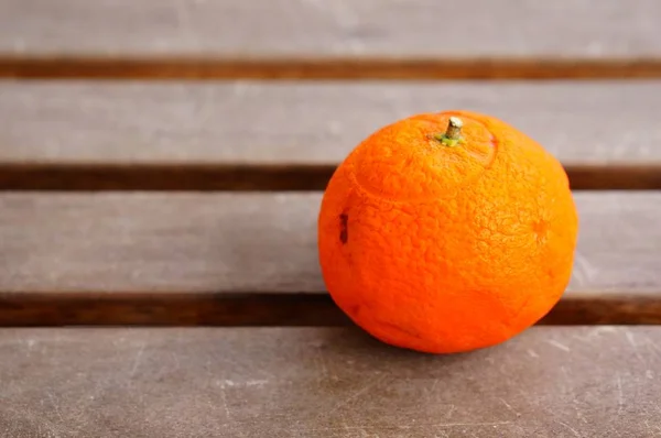 Closeup shot of a fresh tangerine on a wooden surface — Stock Photo, Image