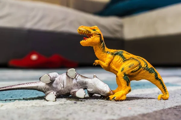 Closeup shot of two toy dinosaurs placed on the ground in the bedroom — 스톡 사진