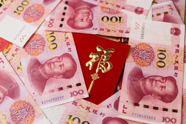 A closeup shot of 100 Chinese Yuan (CNY) banknotes and Chinese traditional red envelop for Chinese New Year